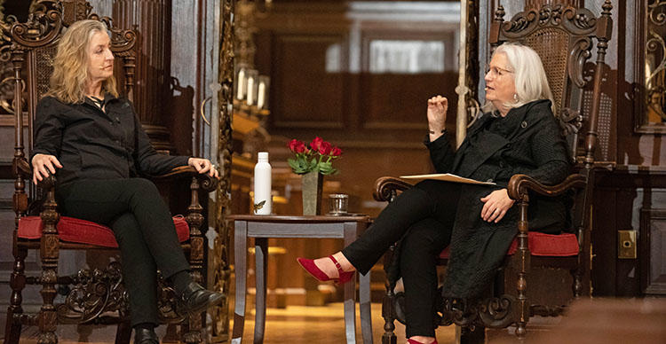 two people sit in chairs and have a conversation