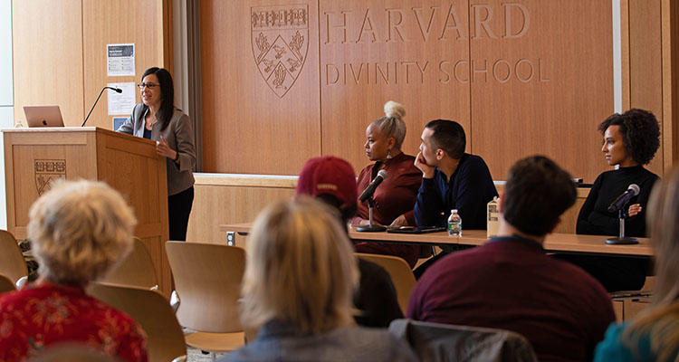 a panel of students listens to a speaker at the podium