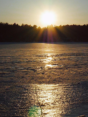 sun setting above frozen pond