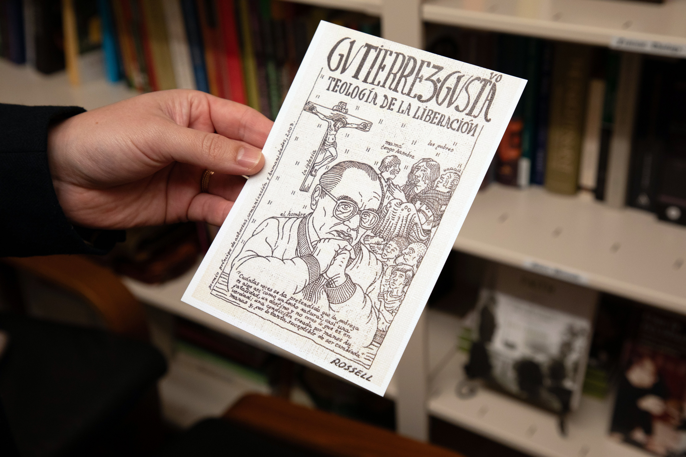 Professor Zegarra holding a book before a book shelf