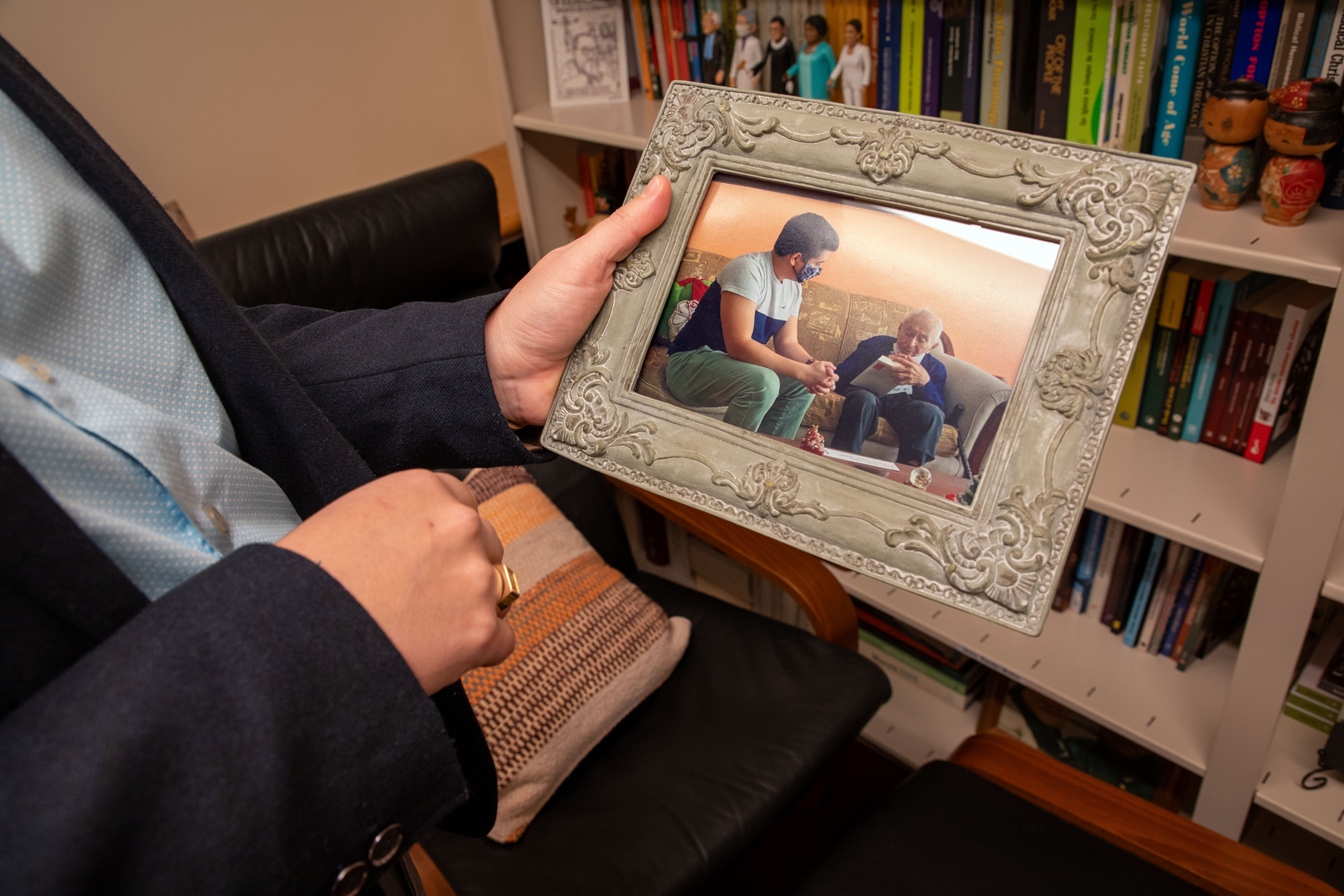 Professor Zegarra holding picture frame in front of books