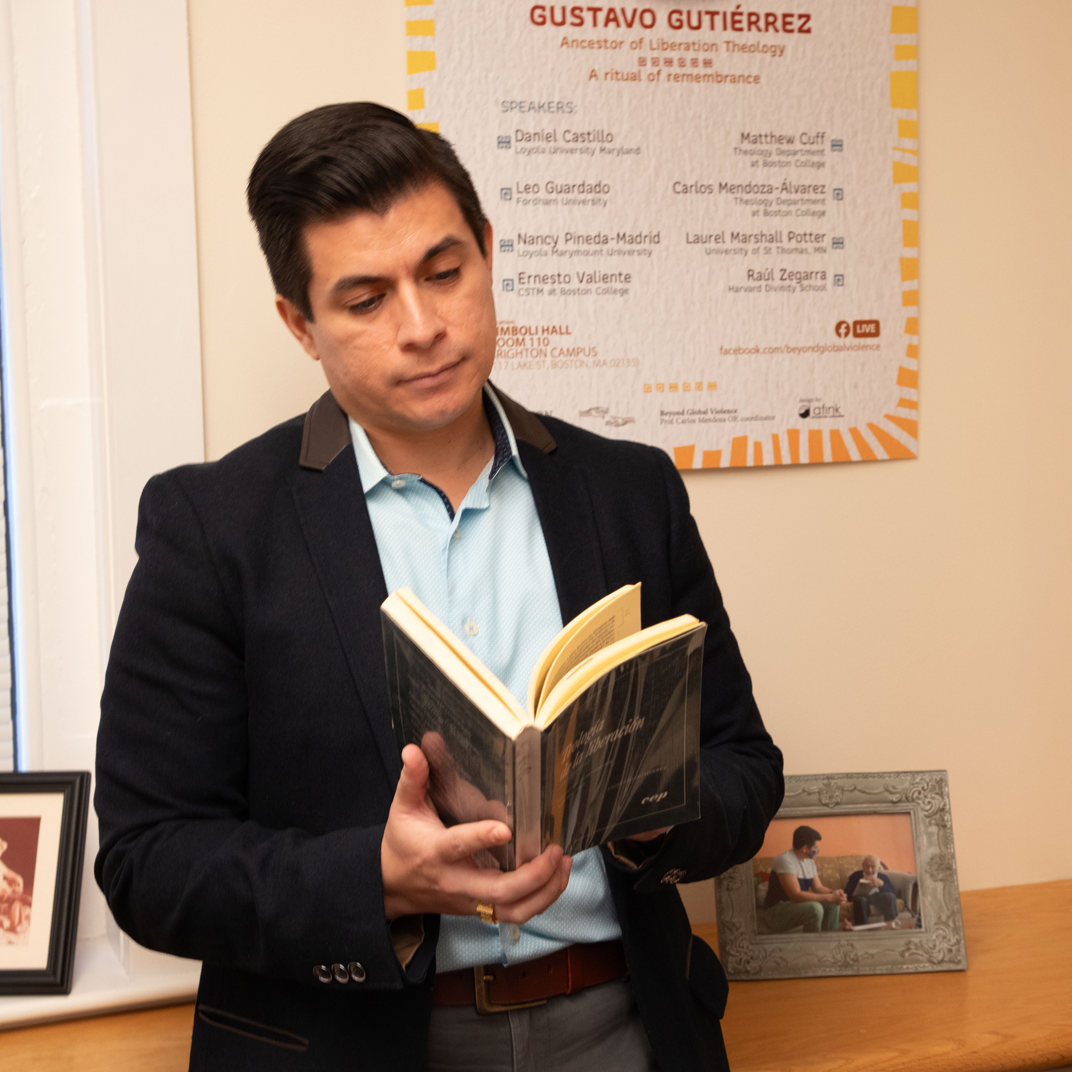 Professor Zegarra stands before shelf reading a book