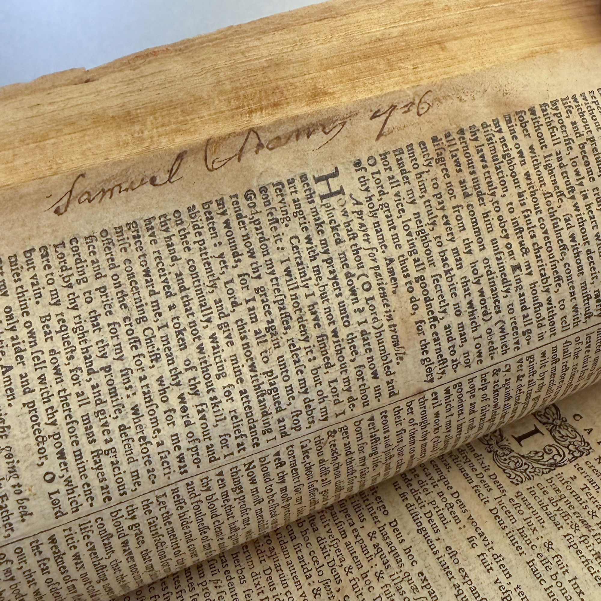 A historic Book of Common Prayer opened to page containing Samuel Adams's signature in the margins of a worn page