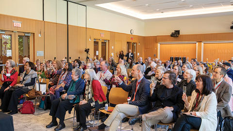 Room of event attendees raising glasses for a toast