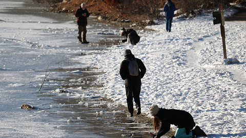 students walk along and explore frozen banks of Walden Pond
