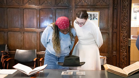 Two HDS students look at artifact in library.