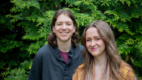 Tess Dufrechou, MDiv ’25, and Kat Woodard, MDiv ’25 pose for photo with green leaves behind them