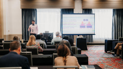 Kevin McIntosh speaking to an audience with a screen to the audience's right