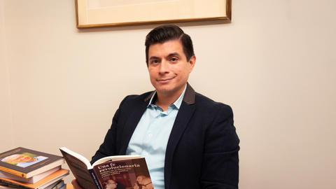 Professor Zegarra holding a book sitting at a table