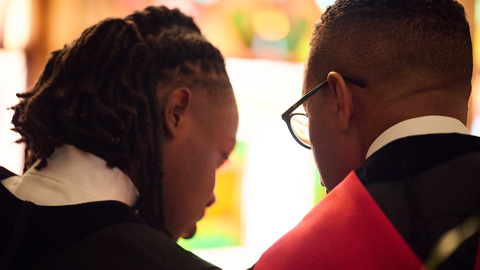 A student talks to his mentor in a chruch. Their backs are to the camera