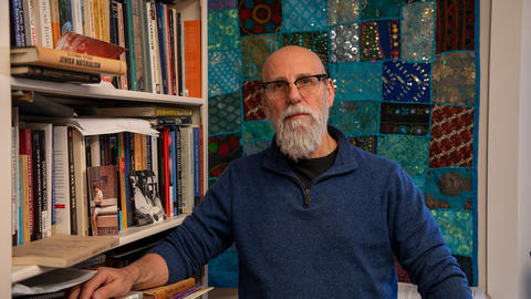 Shaul Magid standing next to bookcase