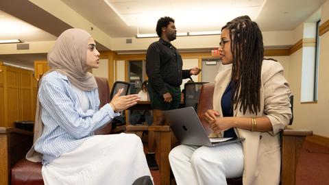 HDS students have a discussion in the library while seated.