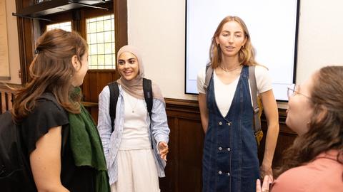 Four students speak with one another in Swartz Hall, in front of main doors