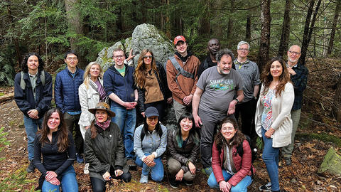 Group photo of people gathered in the woods
