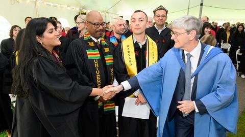 Dean Hempton shakes hands during, all dressed in academic robes