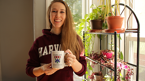 Keila Franks in a Harvard sweatshirt holding a mug.