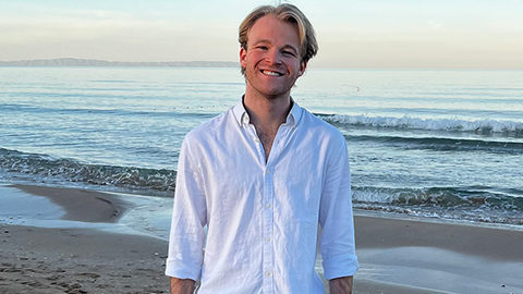Ryan standing in front of the ocean and smiling at the camera