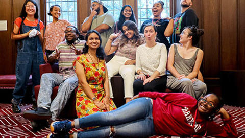 11 students smiling sittin on a couch and standing