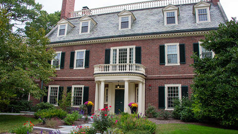 Three-story brick home with a flower-lined path leading to the door