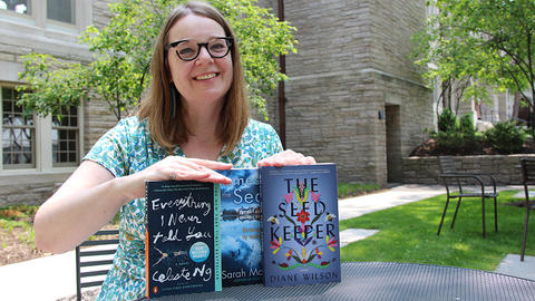 Mary Kiesling sitting at a table holding multiple books