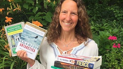 Michelle Goldhaber holding a stack of books outside