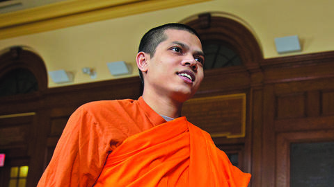 Venerable Priya Rakkhit Sraman, wearing an orange robe, stands inside Divinity Hall Chapel.