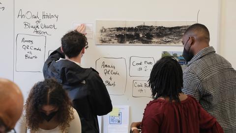 Students with their back to camera work facing a white board.