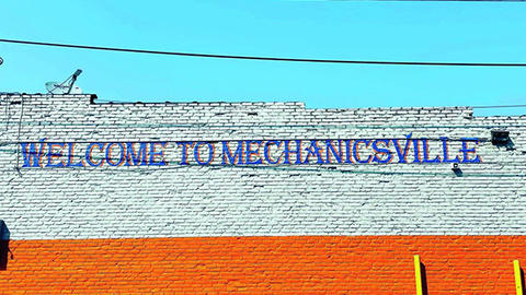 A painted sign on a building reads "Welcome to Mechanicsville"
