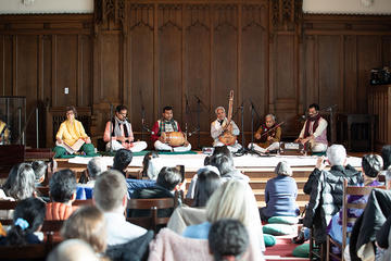 A group of people sit on stage playing instruments