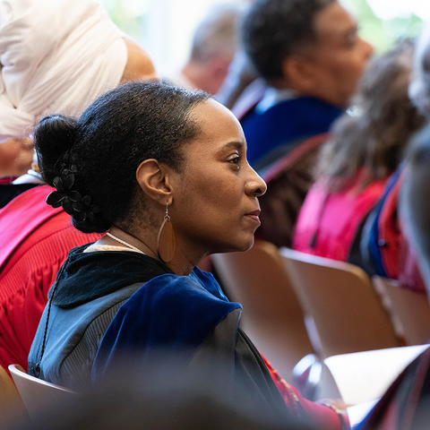 person seated looking on dressed in academic gown