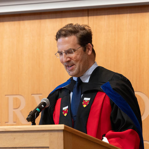 David Holland gives address with light brown background