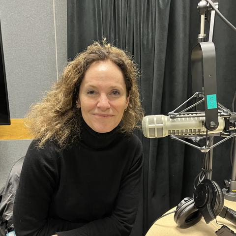 Amy Brenneman headshot with podcast microphone to her left