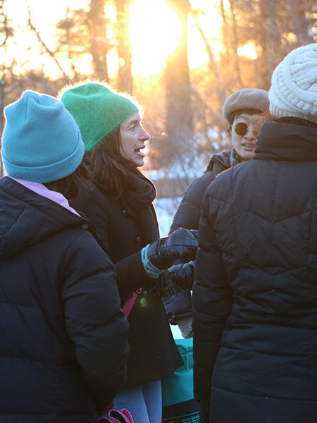 participants discuss in the open air with the setting sun shining through the trees