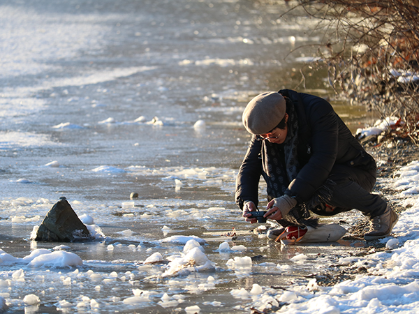 participant crouches on the ice and takes up close photo of frozen lake