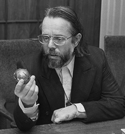 Harvey Cox holding up a small round object