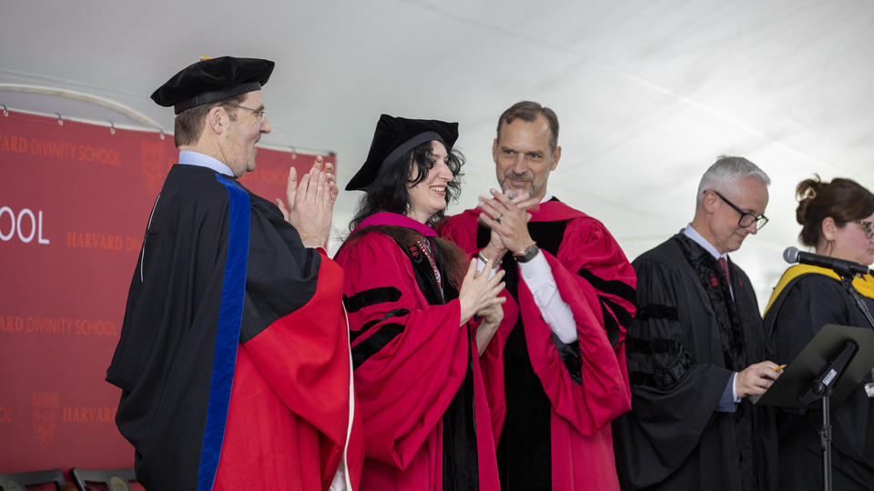 two people clap for a third person in the middle who received a diploma