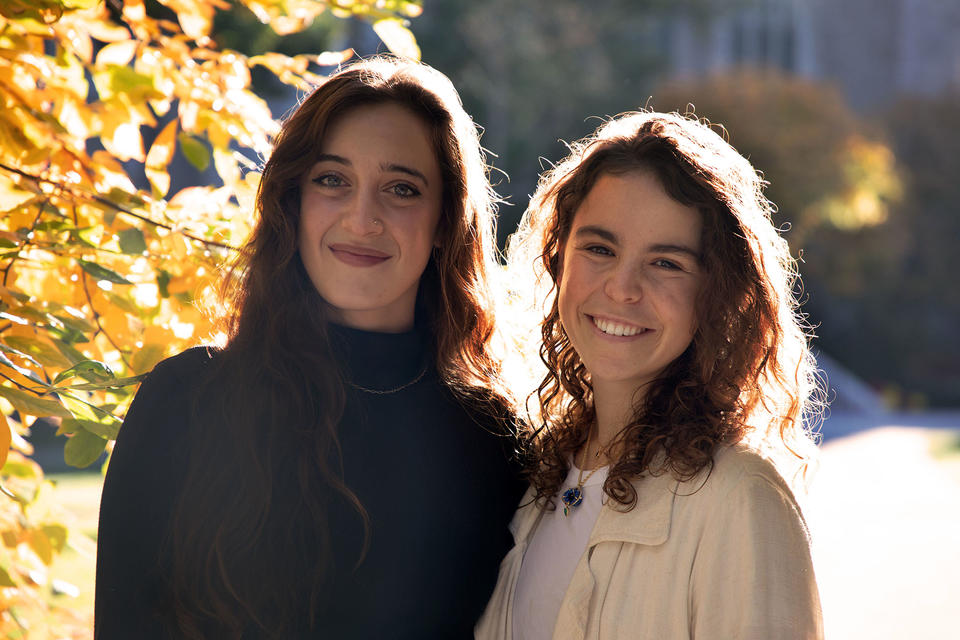 two HDS students pose for photo next to tree with orange leaves