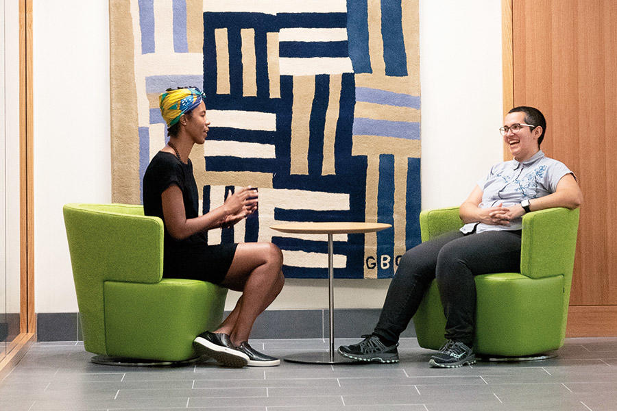 Two students seated in front of a decorative wall rug talking in Swartz Hall