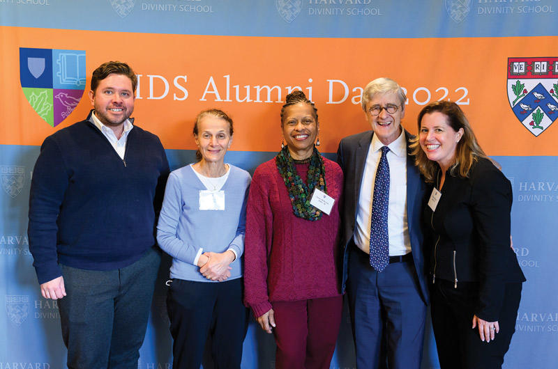 Several HDS alumns posing with Dean Hempton in from of the Alumni Day sign