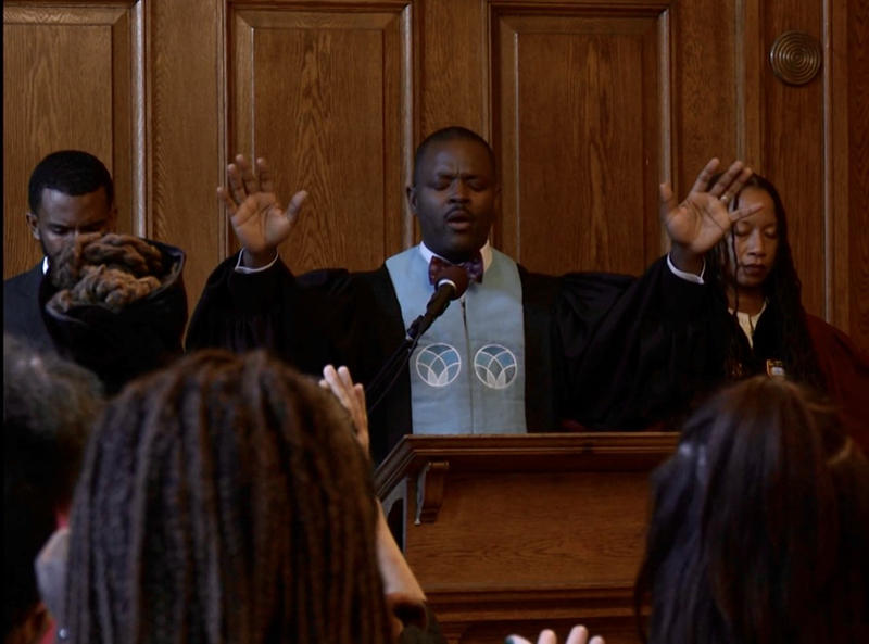 The Rev. Kevin Kitrell Ross raises his arms during a ceremony in Emerson Chapel in Divinity Hall.