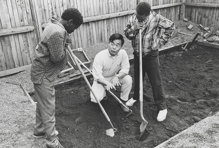 Young man and two children working in a garden