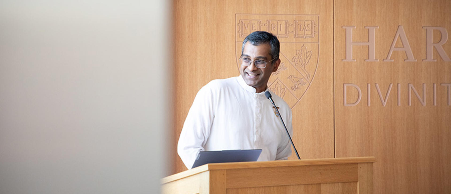 Sundar standing behind lectern with brown background to the right