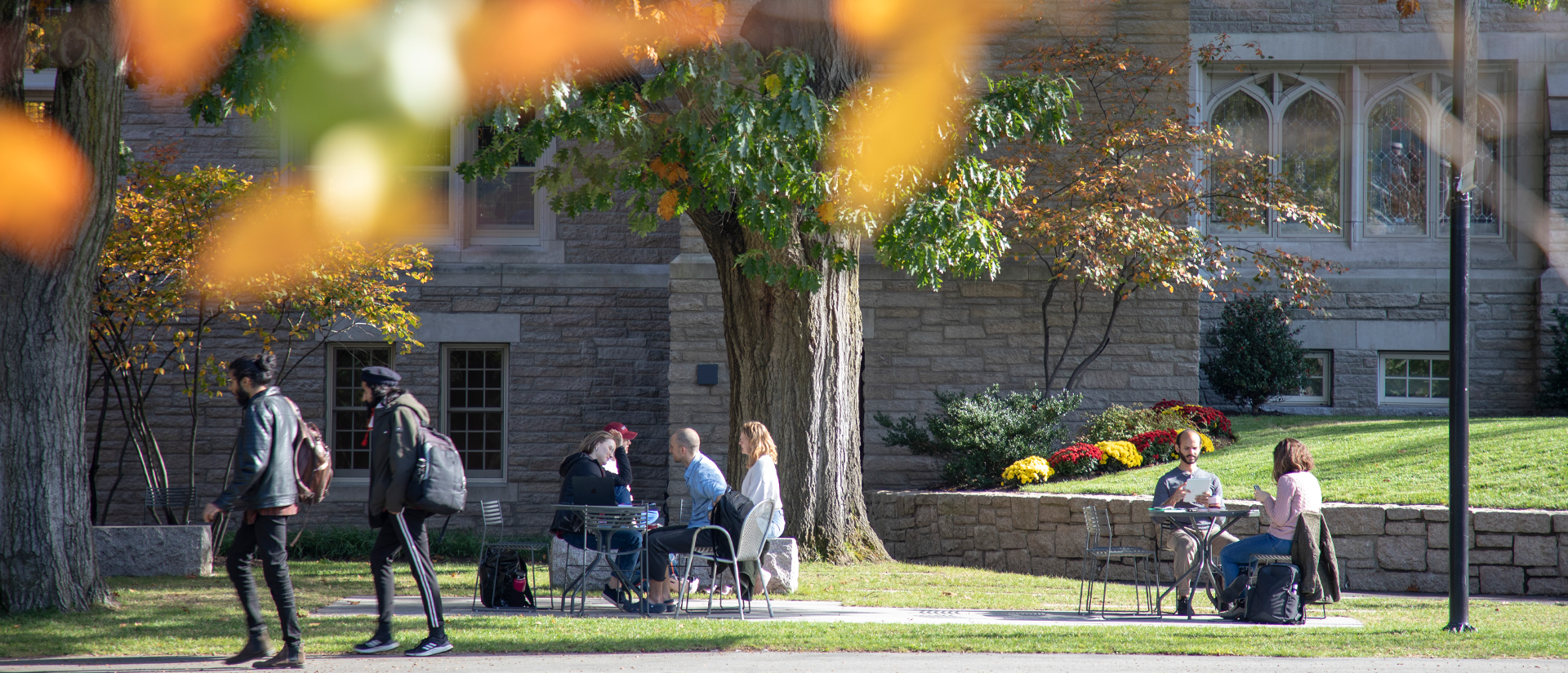 Students walk across the HDS green in early fall. Swartz Hall is behind them