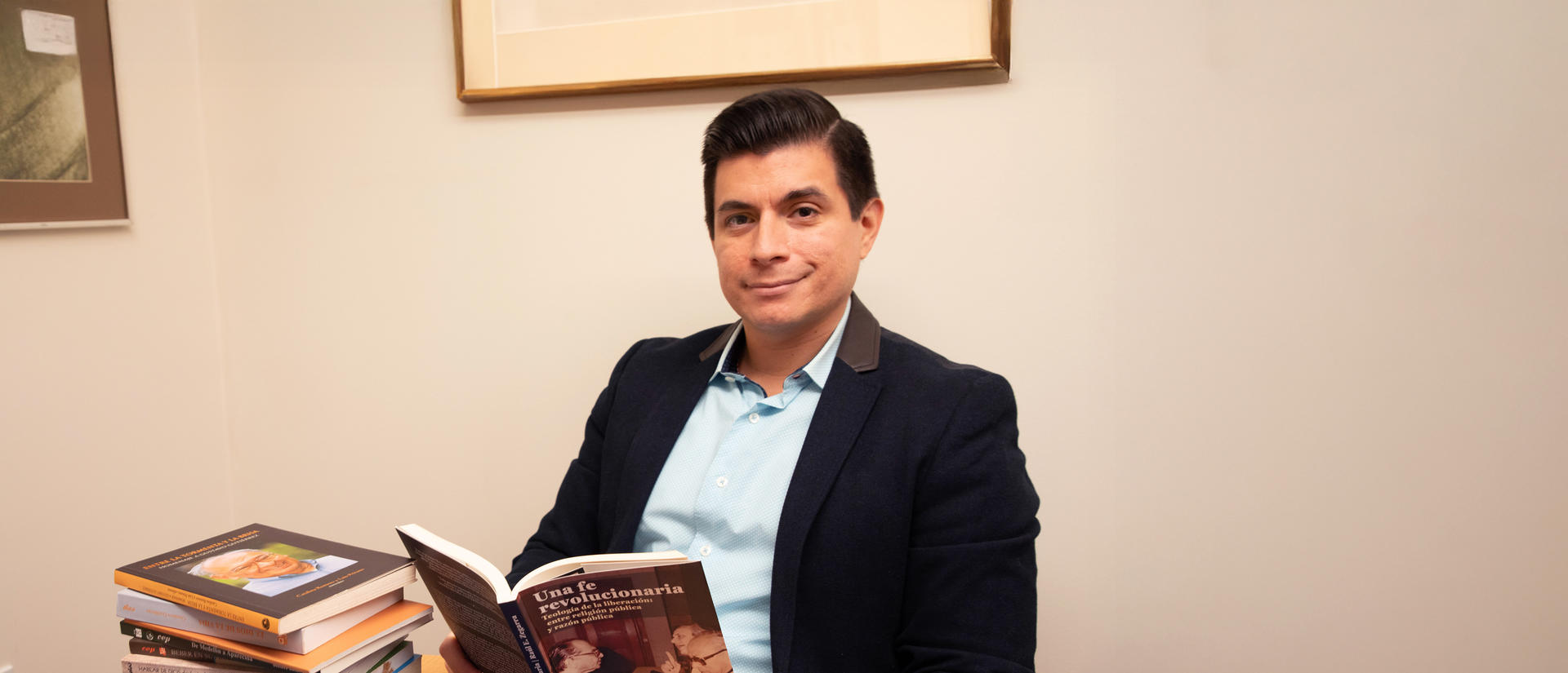 Professor Zegarra holding a book sitting at a table