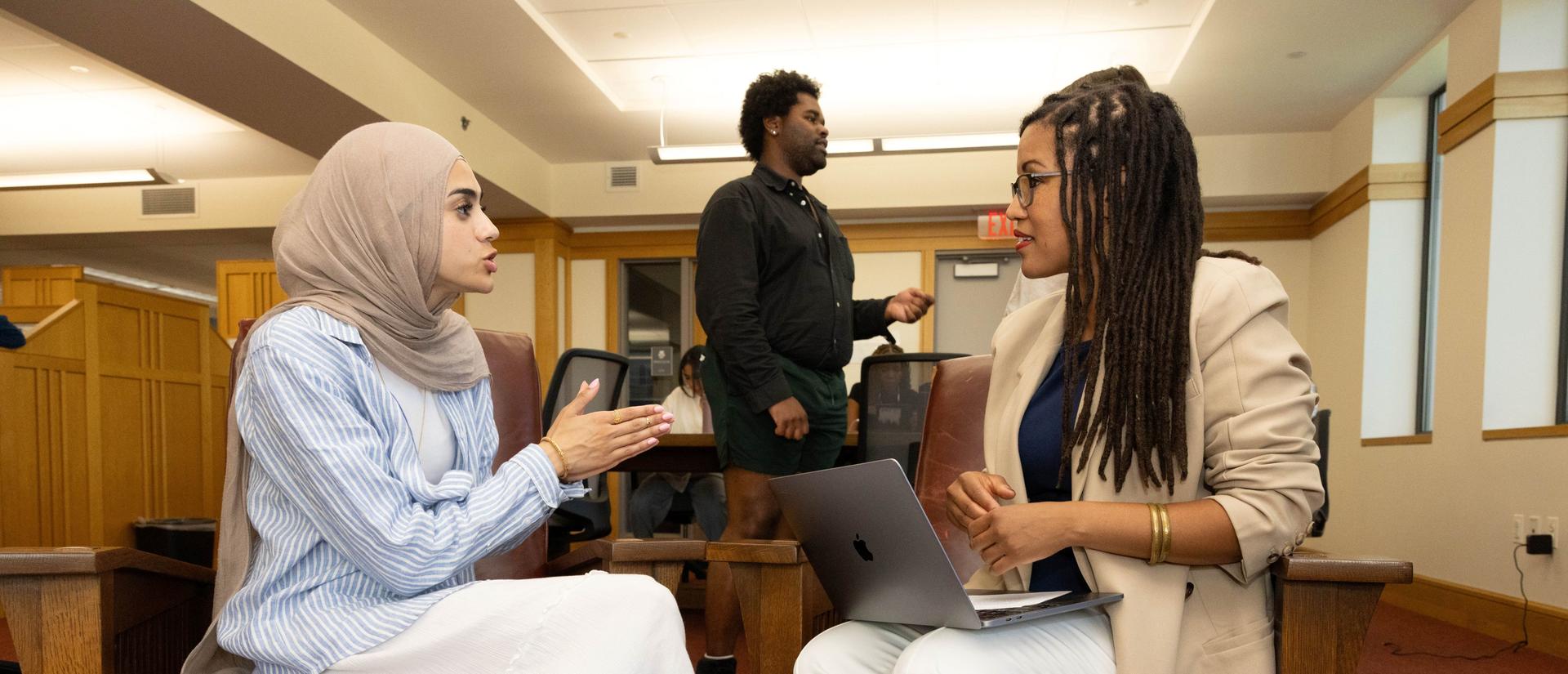 HDS students have a discussion in the library while seated.