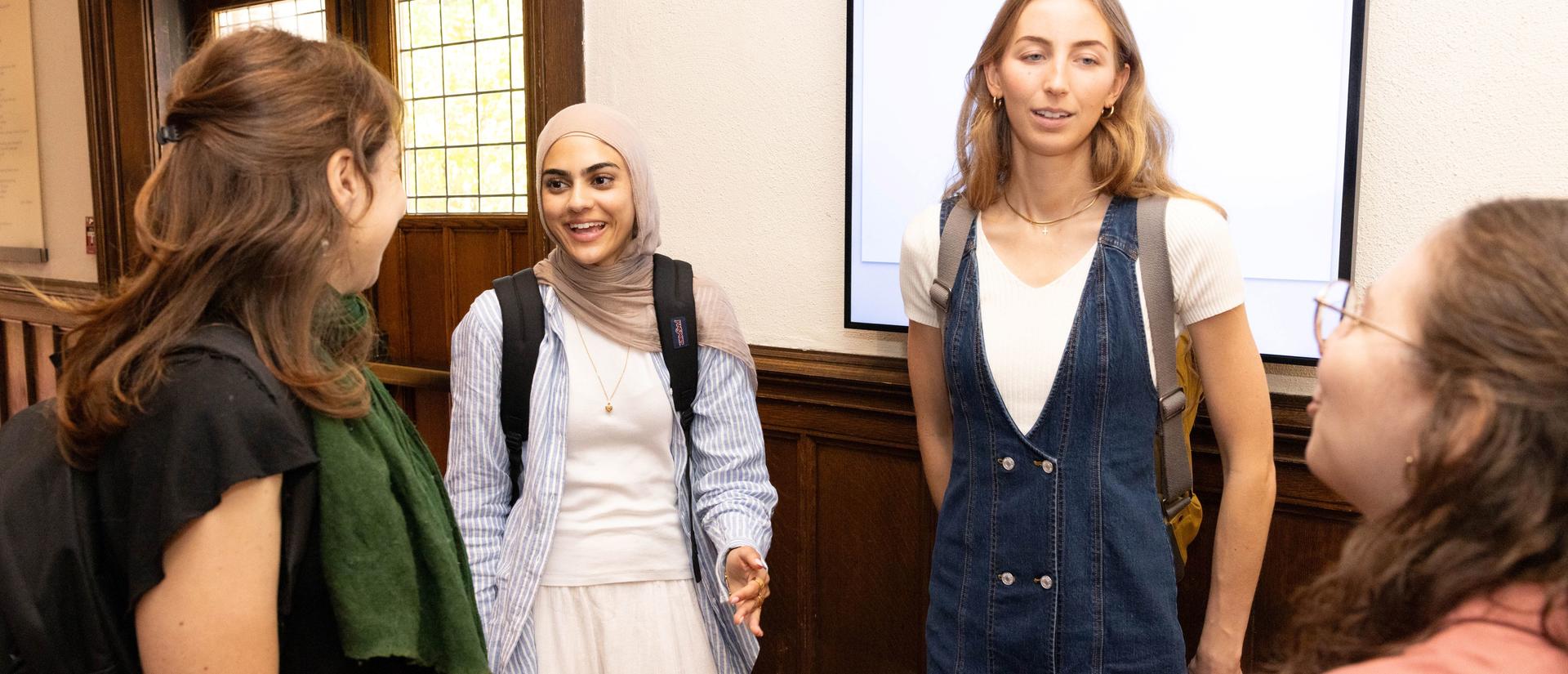 Four students speak with one another in Swartz Hall, in front of main doors