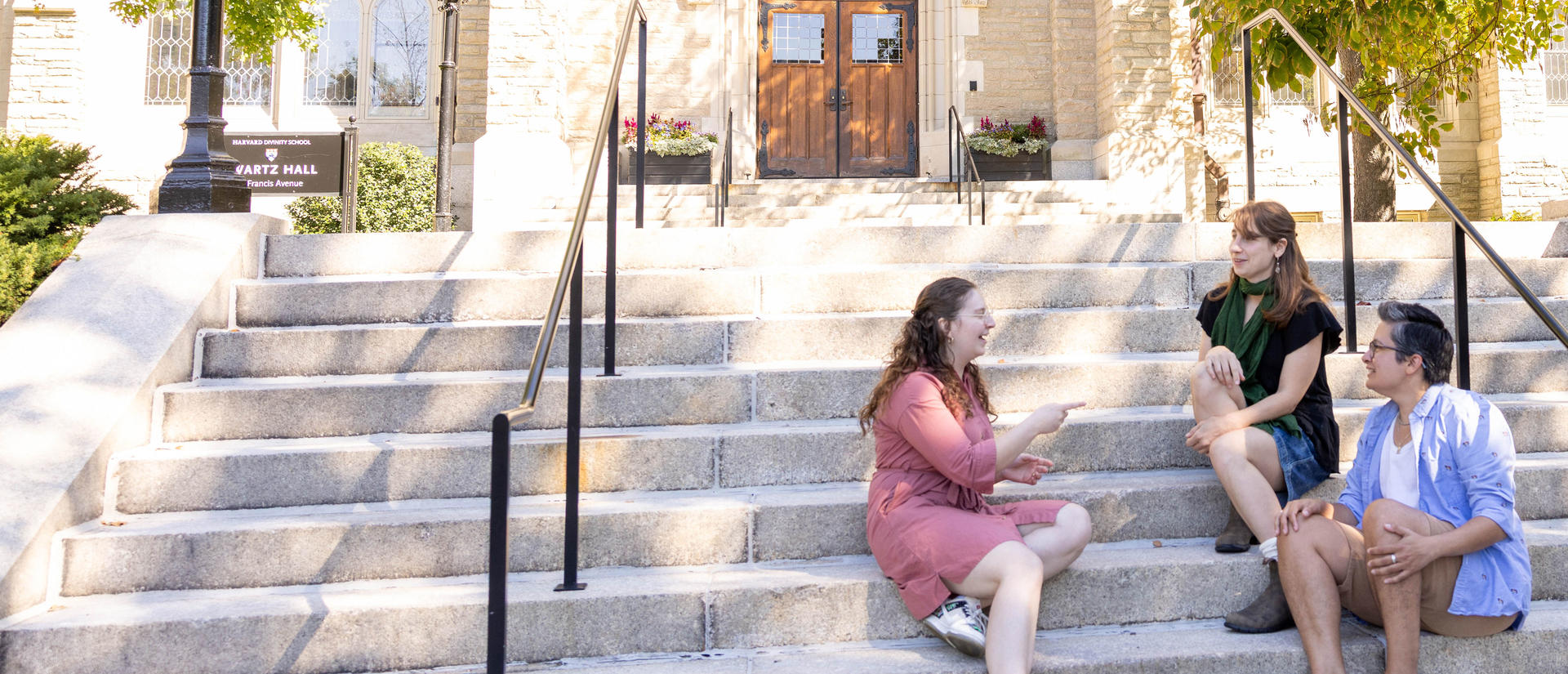Three HDS students sitting on the steps outside Swartz Hall