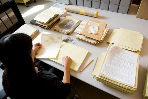 Librarian with collection materials spread out on a table in front of her