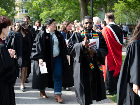 students walk in a line dressed in graduation robes during commencement