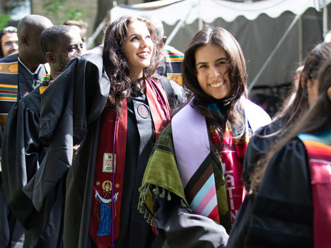 students process in a line wearing graduation robes 
